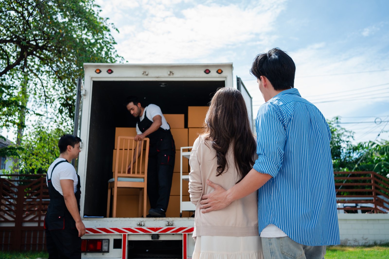 Asian Couple check while unloading boxes and furniture from a pickup truck